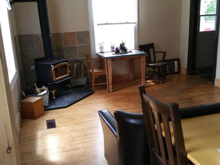 Una sala de estar acogedora con chimenea, piso de madera, una mesa de comedor y un sofá.