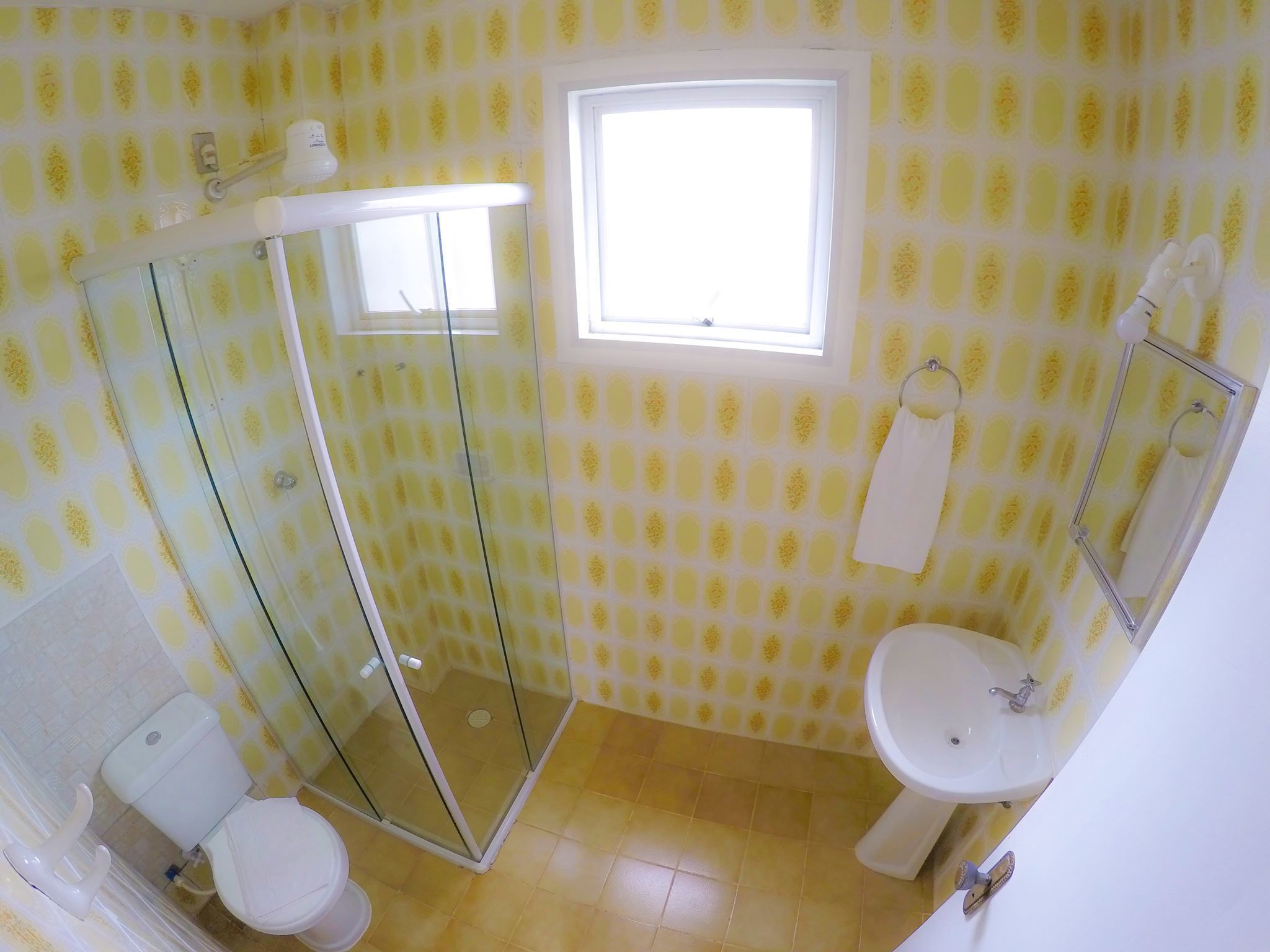 Une salle de bain avec une douche à parois de verre, des toilettes, un lavabo et une fenêtre.