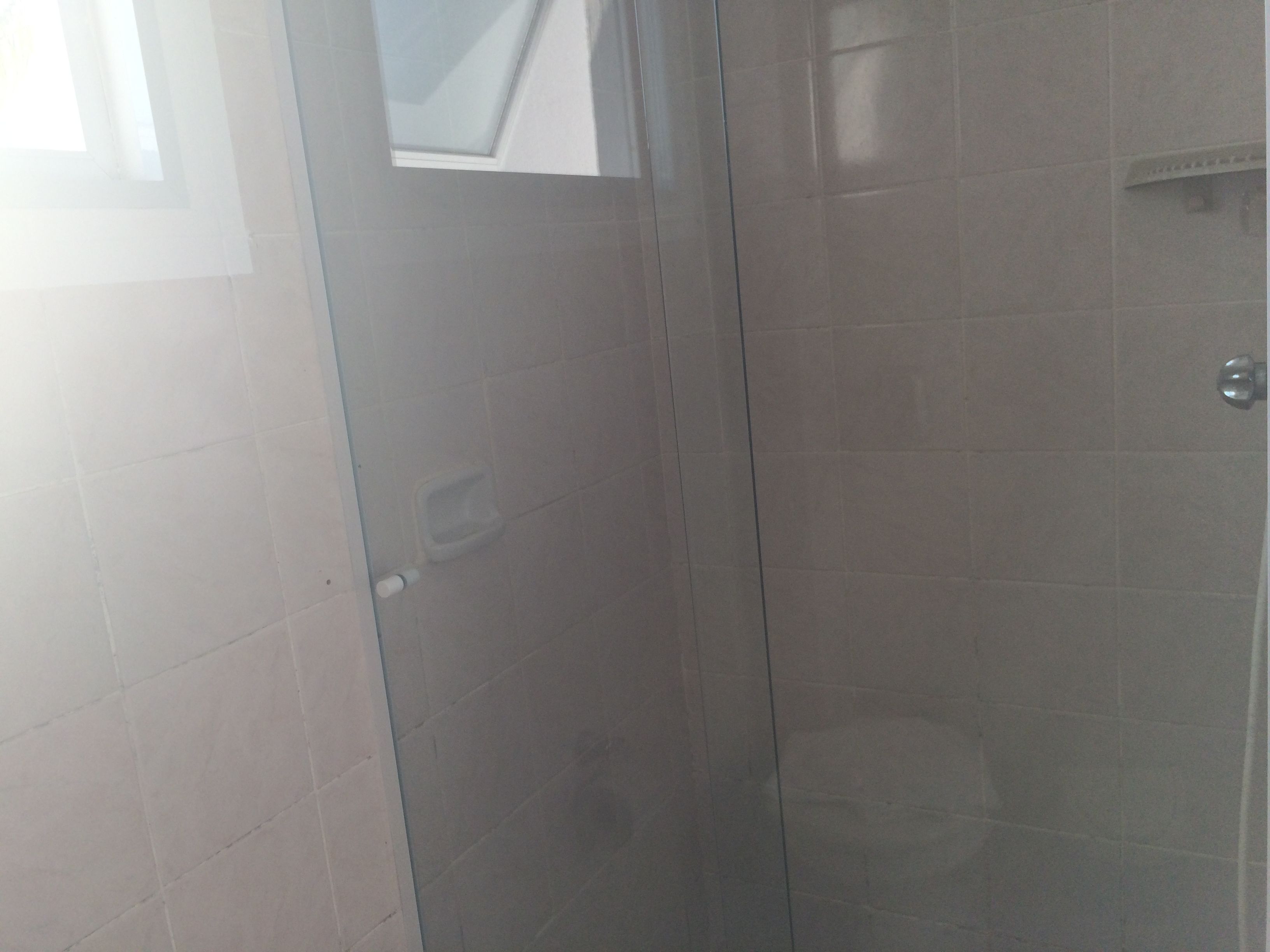 Un baño con cabina de ducha de vidrio, inodoro y una pequeña ventana.