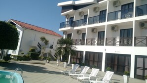 Un hôtel doté de nombreux balcons, de systèmes de climatisation et d’un espace piscine avec des chaises longues.