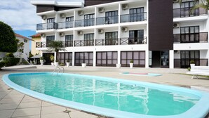 Un bâtiment moderne doté d’une piscine, de nombreux balcons et de systèmes de climatisation.