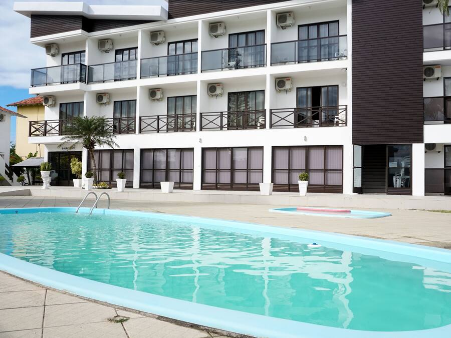 Un edificio moderno con piscina, varios balcones y unidades de aire acondicionado.