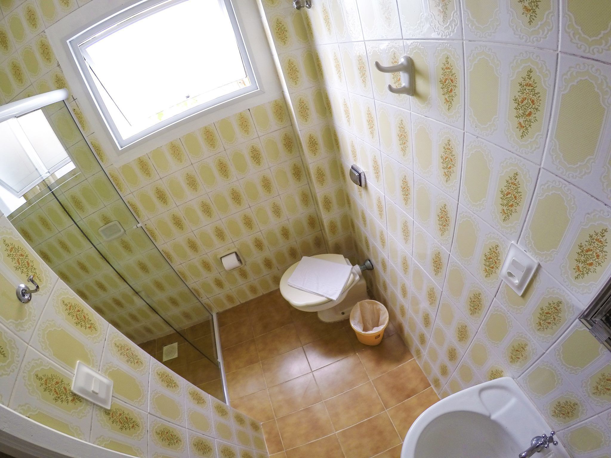 A bathroom with patterned tiles, a toilet, a sink, and a window.