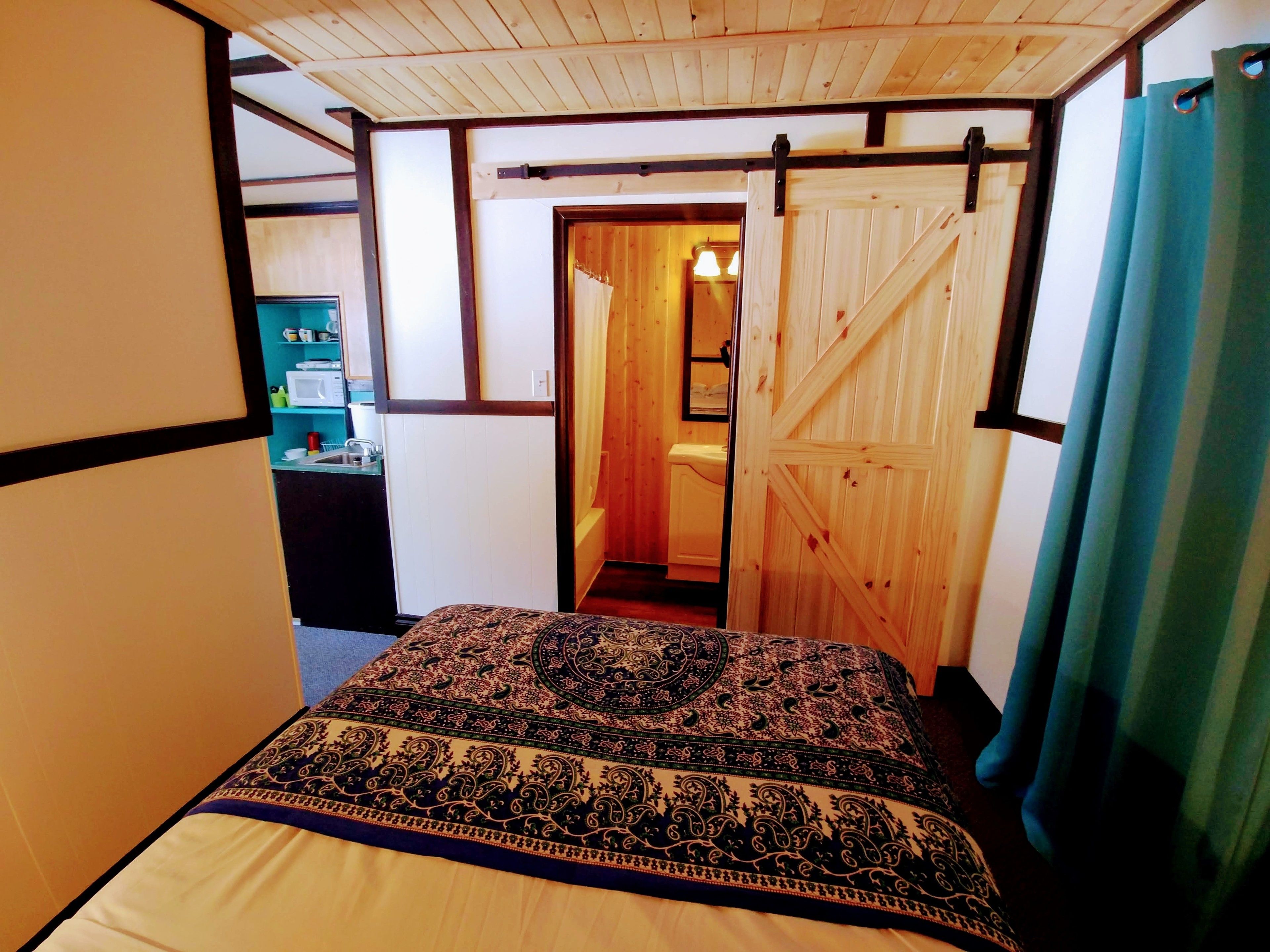 Un dormitorio con cama, una puerta de madera y vistas a otra habitación.