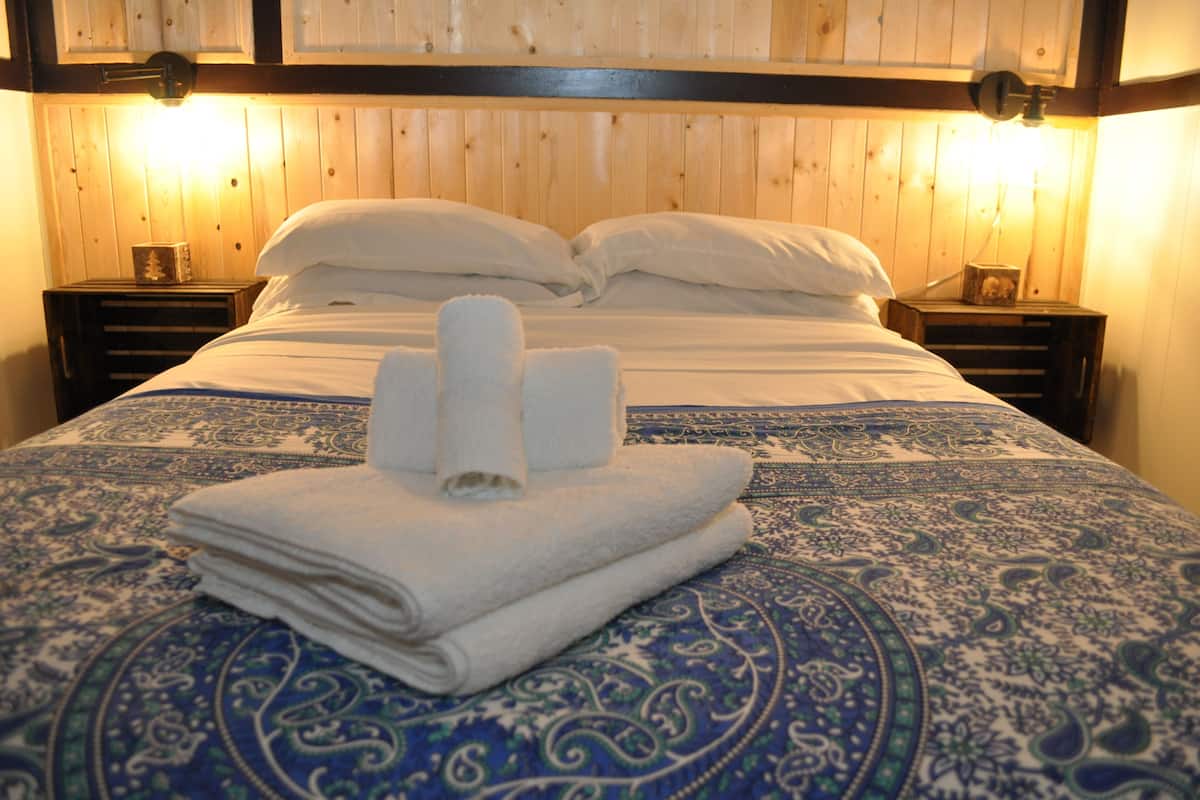 A neatly made bed with a blue patterned bedspread and two bedside tables with lamps.