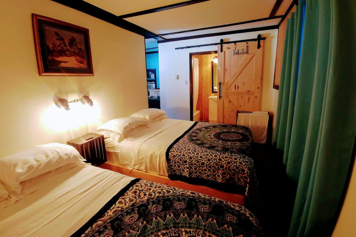 A room with two beds, a wooden door, and a green curtain.