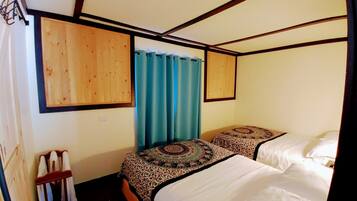 A bedroom with two beds, wooden headboards, a blue curtain, and a wooden wall panel.