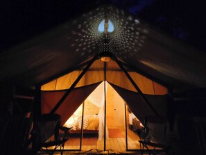 Ein Zelt mit einem Bett in der Mitte und Stühlen darum herum.