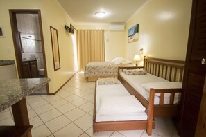 A hotel room with a bed, a bedside table, a mirror, a window with curtains, and a bathroom visible through an open door. - San Diego Apart Hotel (Florianopolis)