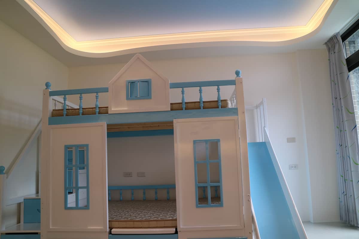 A bunk bed with a small attic room, white walls, and a staircase.