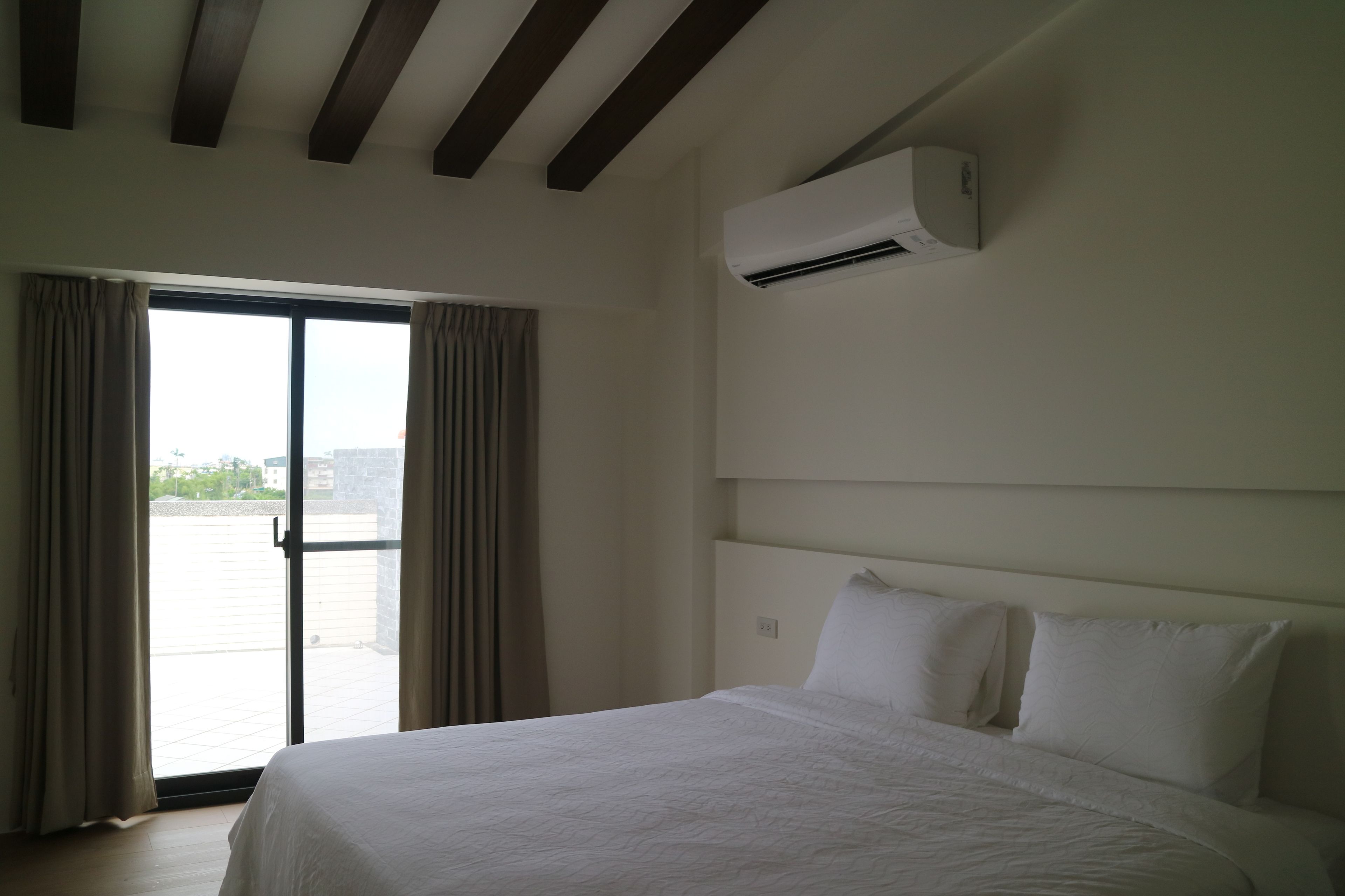 Une chambre d’hôtel équipée d’un lit, d’un appareil de climatisation, d’une porte-fenêtre coulissante et offrant une vue sur l’extérieur.