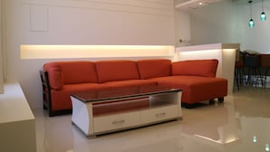 A modern living room with a red sofa, a glass coffee table, and a white accent wall. - Manman B&B (Sanxing)