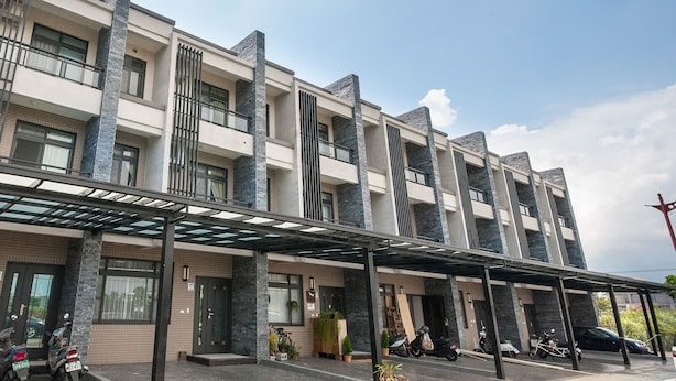 A multi-story building with a modern architectural design, featuring a covered entrance area with a glass canopy, and several balconies. - Manman B&B (Sanxing)