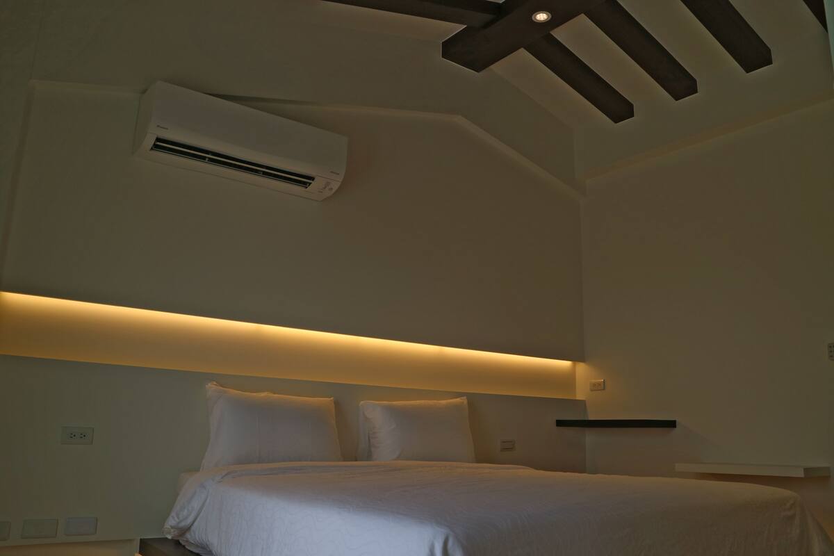 A hotel room with a bed, an air conditioning unit, and a ceiling fan.
