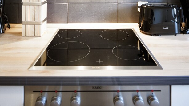 A modern kitchen with a stainless steel stove, a built-in oven, and a range hood. - City Park Apartment 23 (Leipzig)