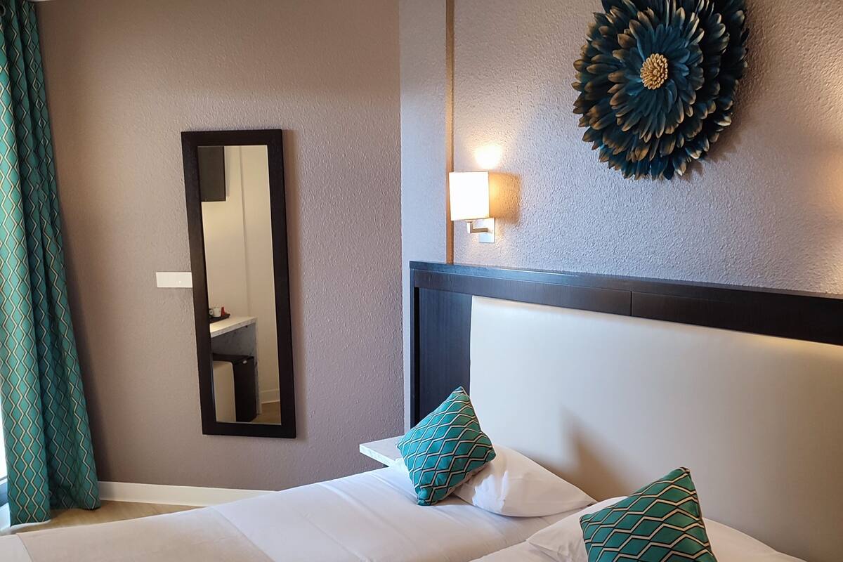 Habitación de hotel con dos camas, un espejo grande, una lámpara de pared y un adorno mural.