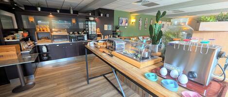A cafe with a wooden counter, a coffee machine, and a display of pastries.