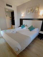 A hotel room with a large bed, two bedside tables, a headboard, and a wall-mounted artwork.