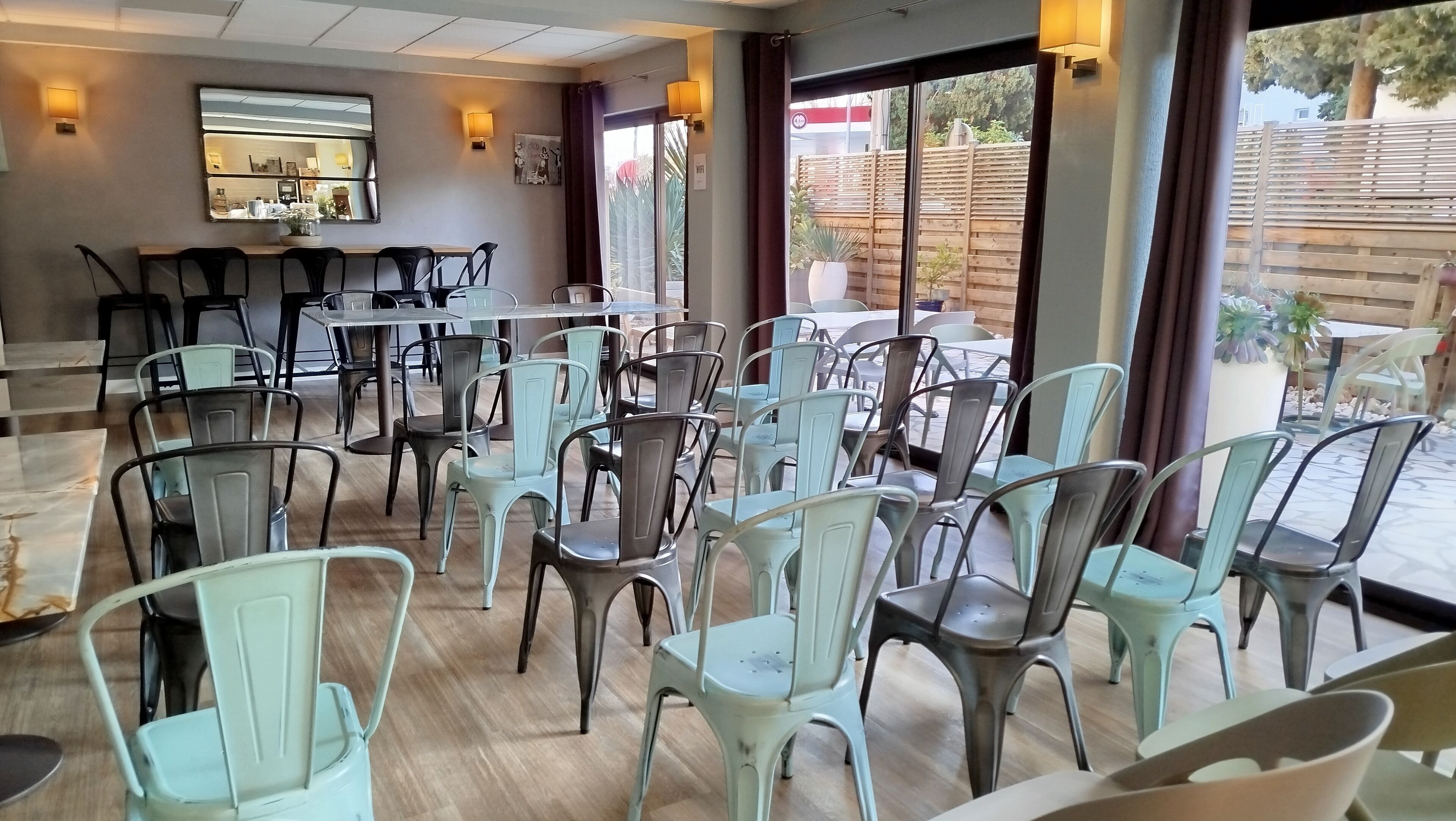 Un ristorante con diversi tavoli e sedie, ampie finestre e vista all'esterno.