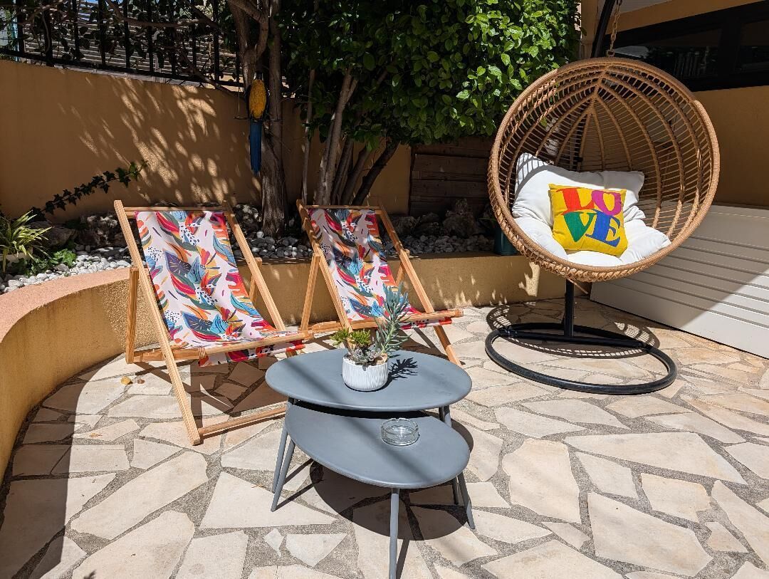 Un espace extérieur aménagé avec deux fauteuils de jardin, une petite table et une chaise en osier.