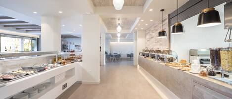 A modern buffet area with a long counter, multiple food stations, and pendant lighting.