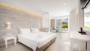 A modern hotel room with a large bed, a desk, and a balcony with a view. - Apollon Windmill Hotel (Kos)