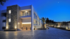 A modern building with a stone facade, multiple balconies, and a paved courtyard. - Apollon Windmill Hotel (Kos)