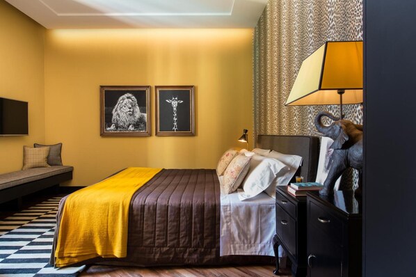 A bedroom with a bed, bedside table, lamp, and artwork on the wall. - Velona's Jungle Luxury Suites (Florence)