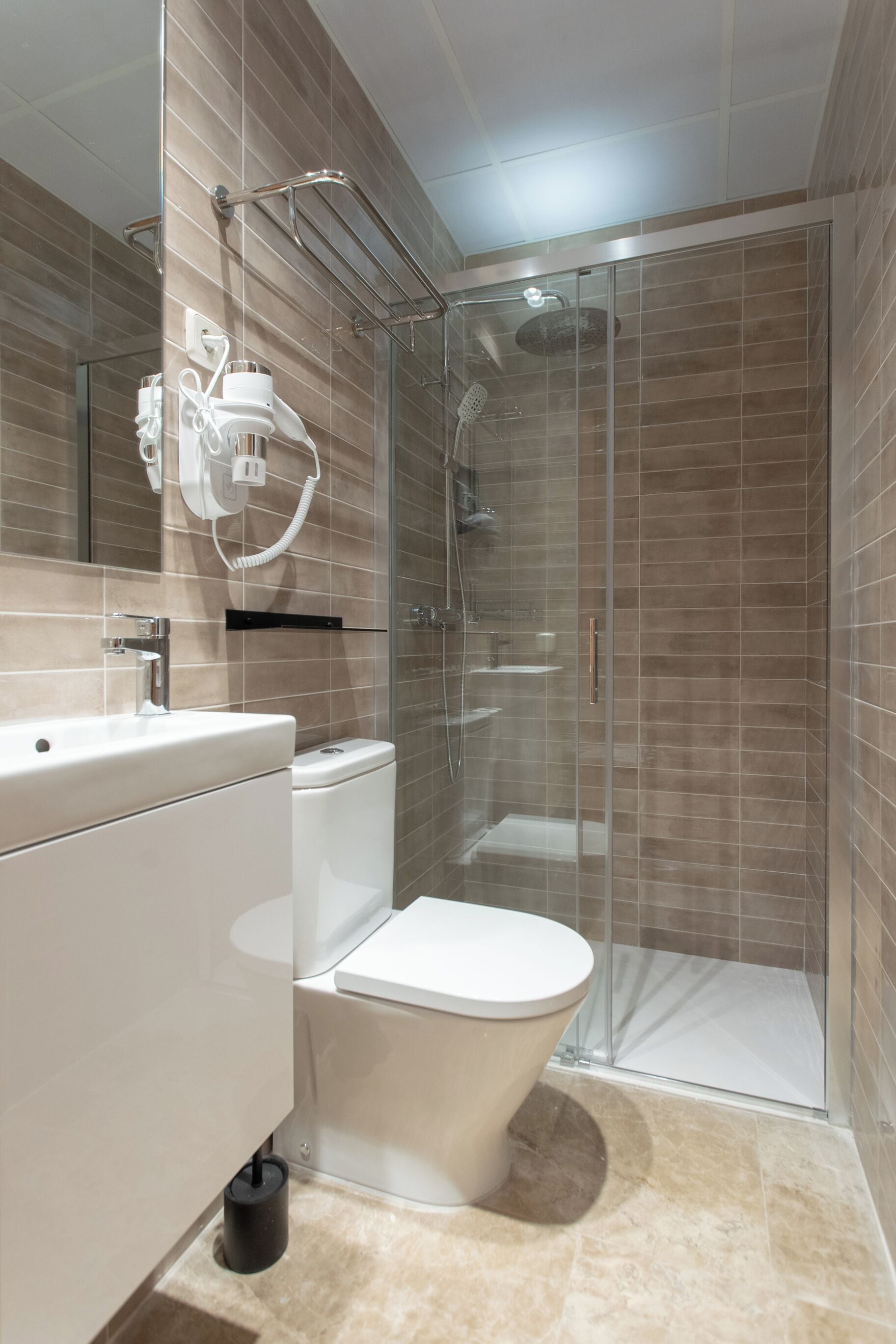 A modern bathroom with a glass-enclosed shower, a white toilet, and a vanity with a mirror.