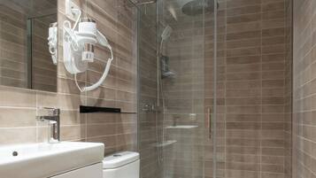 A modern bathroom with a glass-enclosed shower, a white toilet, and a vanity with a mirror.