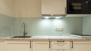 A kitchen with a sink, a microwave, and cabinets. - Suites You Opera (Madrid)