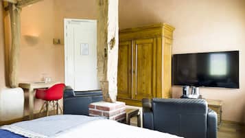 Una habitación con una cama, televisión, un mueble de madera y una silla roja.