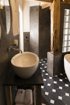 A bathroom with a large vessel sink, a wooden column, and a tiled floor. - Herberg de Kemper (Markelo)