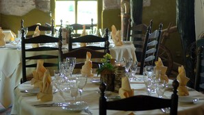 Una mesa de comedor dispuesta con manteles blancos, cristalería y servilletas dobladas con cuidado.