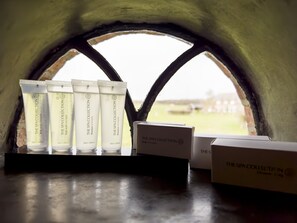 A set of spa collection products displayed in a window with a view of a grassy field. - Herberg de Kemper (Markelo)