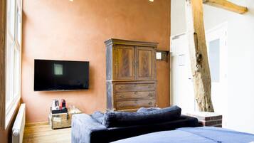 Een slaapkamer met een bed, een houten dressoir, een televisie en een raam.