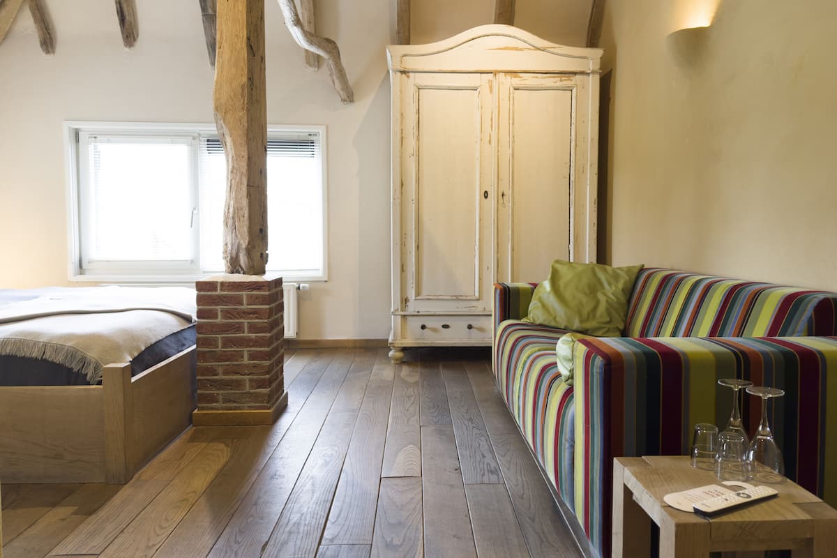 Une pièce comprenant un lit, un canapé rayé aux couleurs vives, une commode en bois et une armoire blanche.