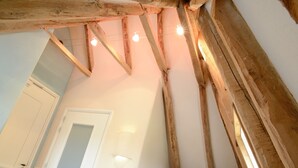 Una habitación con vigas de madera a la vista, una puerta blanca y un aplique.