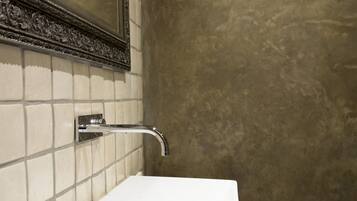 A bathroom with a white sink, a mirror with an ornate frame, and a textured wall.