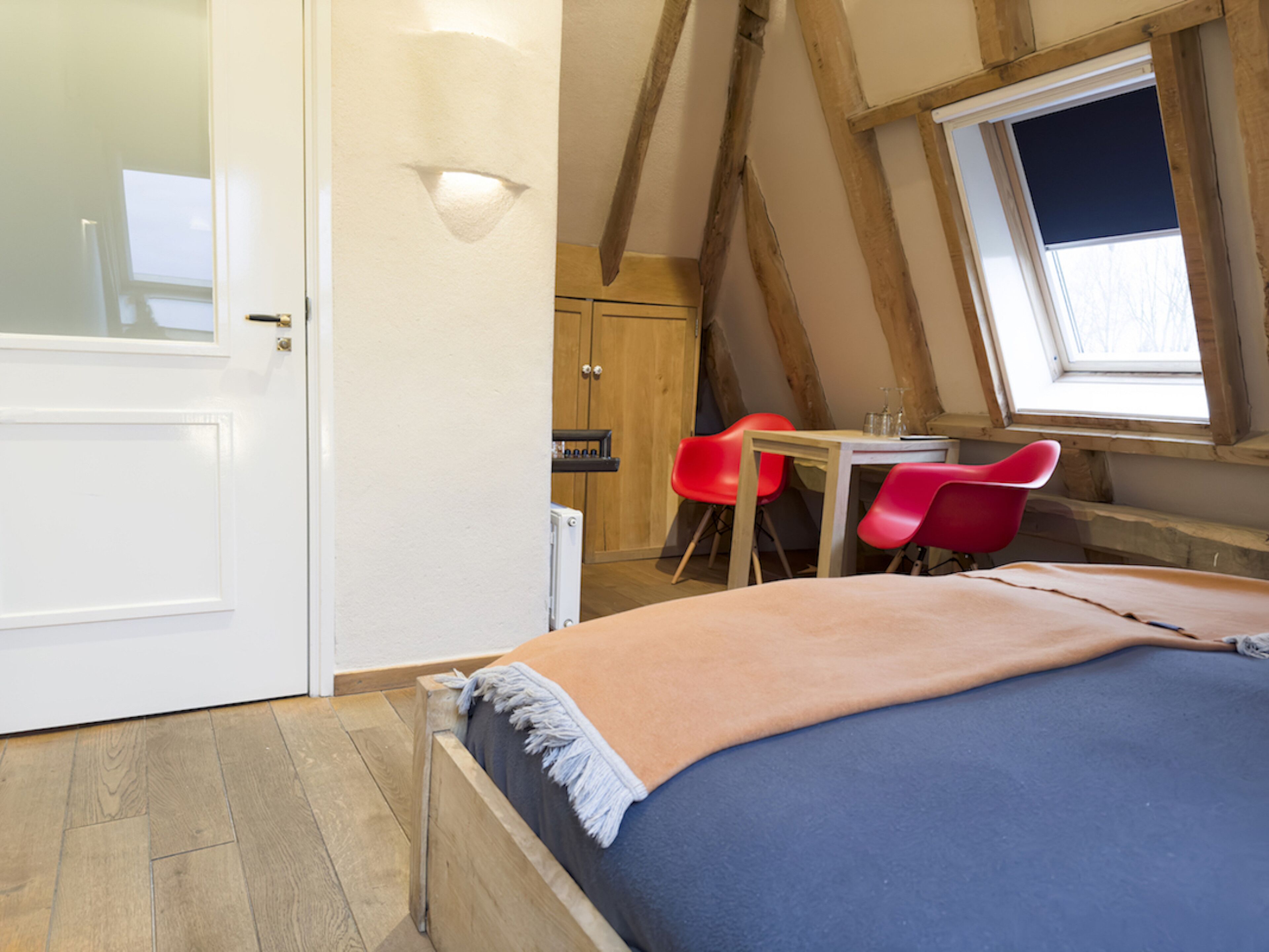 A bedroom with a bed, a window, and a red chair.