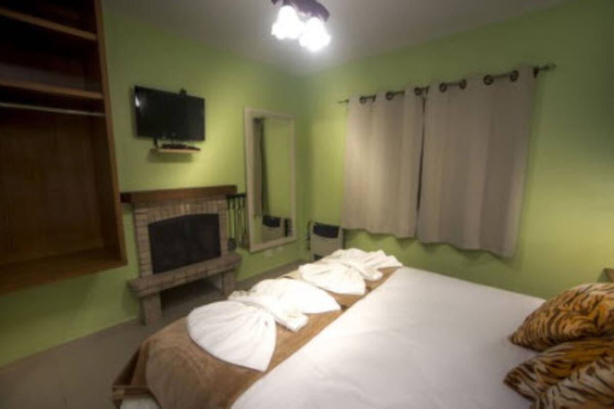 Una habitación de hotel con cama, televisión, chimenea y ventana con cortinas.