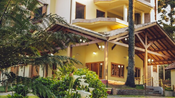 Un edificio a più piani con un'area esterna coperta e una vegetazione rigogliosa in primo piano.