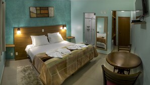 Una camera d'albergo con un letto, una sedia, uno specchio e una televisione.