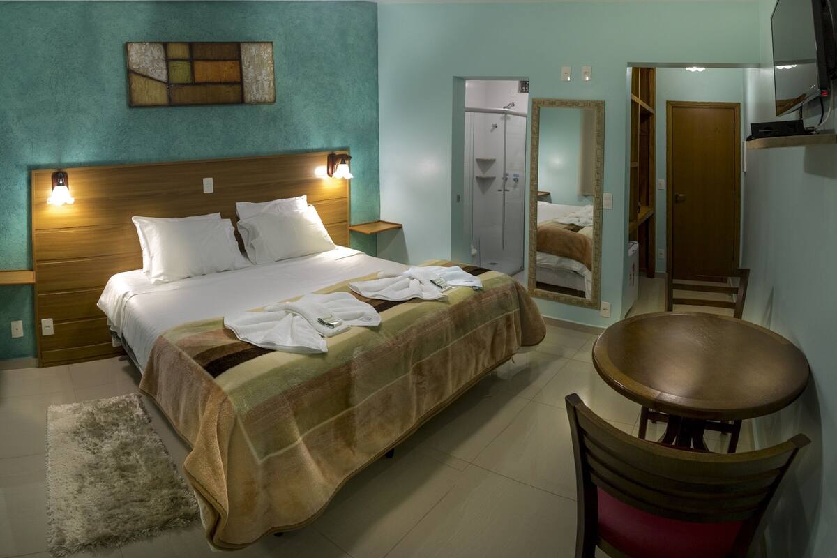 Una habitación de hotel con cama, una silla, un espejo y televisión.