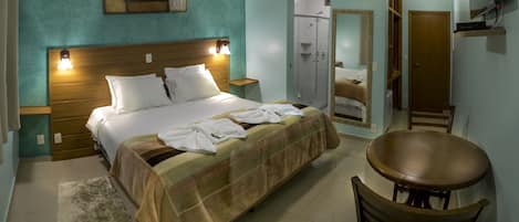 A hotel room with a bed, a chair, a mirror, and a TV.