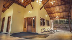 Un'ampia area interna con soffitto in legno a volta, più lampadari e una zona relax con poltrone.