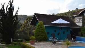 Un área de piscina con suelo de piedra, una sombrilla blanca y mobiliario de exterior.