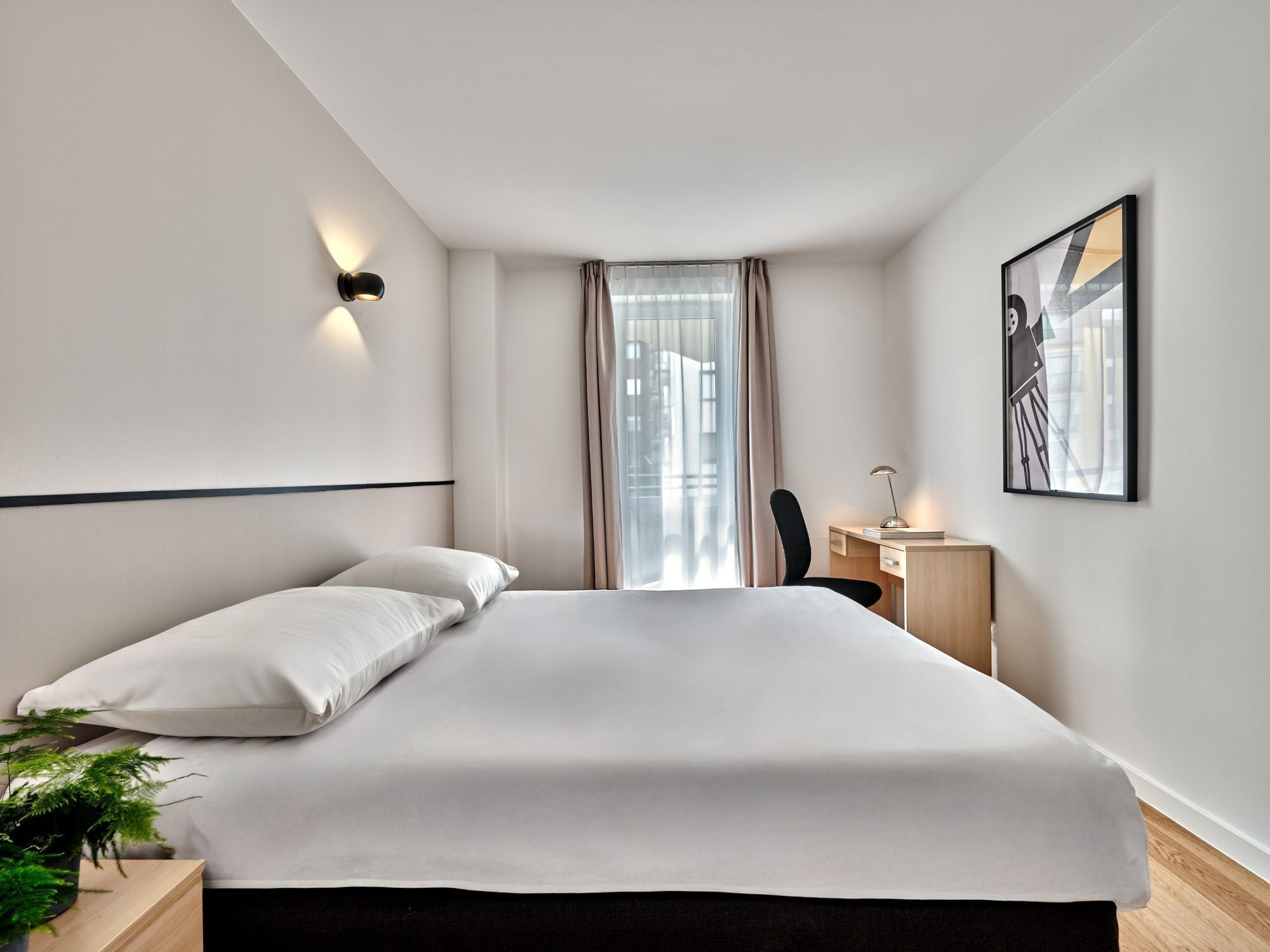 Ein modernes Hotelzimmer mit einem großen Bett, einem Schreibtisch und einem Sessel.