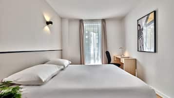 Ein modernes Hotelzimmer mit einem großen Bett, einem Schreibtisch und einem Sessel.