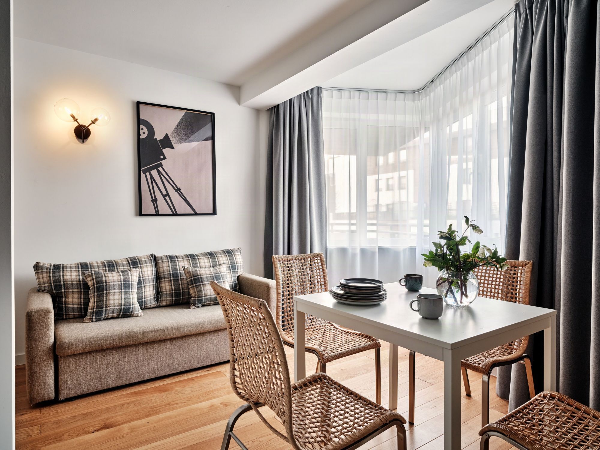 A modern living room with a sofa, dining table, chairs, and a wall-mounted light fixture.